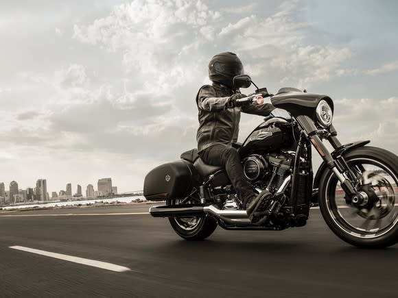 Rider on a Harley-Davidson Sports Glide with a city skyline in the distance