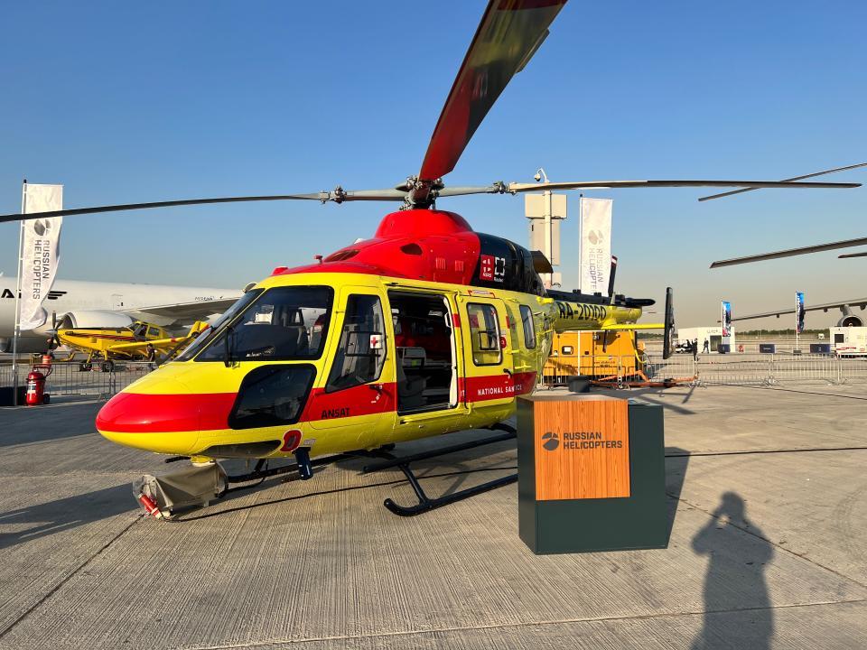 A Kazan Ansat helicopter in yellow, red and black equipped as an air ambulance