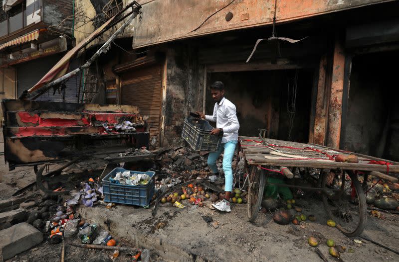 A shopkeeper salvages his belongings from his damaged shop that was set on fire by a mob in a riot affected area after clashes erupted between people demonstrating for and against a new citizenship law in New Delhi