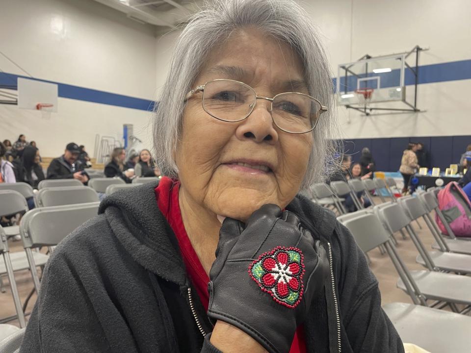 Gina Ondola poses for a photo ahead of the start of the Indigenous People's Day Celebration in Anchorage, Alaska, on Monday, Oct. 8, 2023. Ondola, a Dena'ina Athabascan from Anchorage, displays gloves with red and white beadwork, representing her family's colors. (AP Photo/Mark Thiessen)