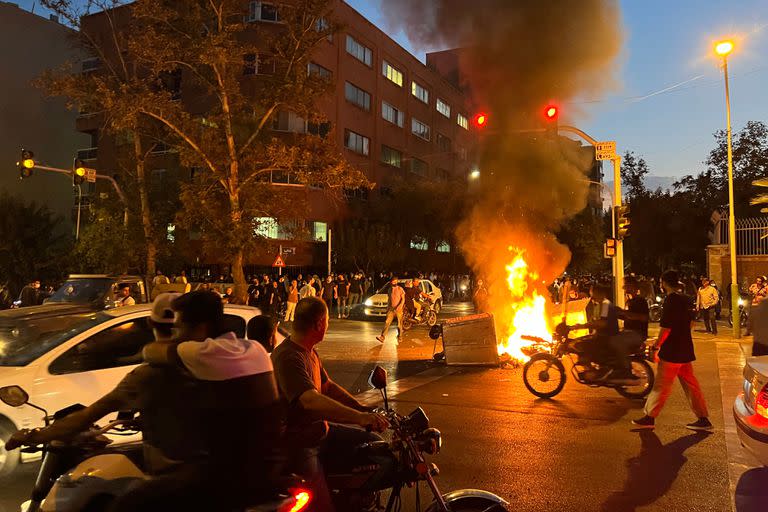 Manifestantes se reúnen alrededor de una barricada en llamas durante una protesta por Mahsa Amini, una mujer que murió tras ser detenida por la "policía de la moral" de la república islámica, en Teherán el 19 de septiembre de 2022.