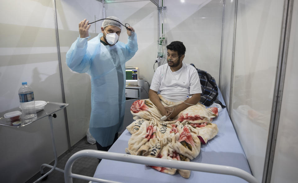 Doctor Malek Imad treats 34-year-old COVID-19 patient Everton Barbosa Godoy at the emergency unit of a field hospital in Ribeirao Pires, greater Sao Paulo area, Brazil, Tuesday, April 13, 2021. (AP Photo/Andre Penner)