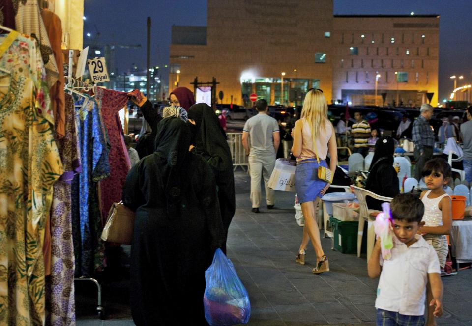 FILE - A foreign woman wearing a short dress walks at Souq Waqif in Doha, Qatar, Monday, June 2, 2014. Qatar has sought to portray itself as welcoming foreigners to this hereditarily ruled emirate, where traditional Muslim values remain strong.(AP Photo/Razan Alzayani, File)