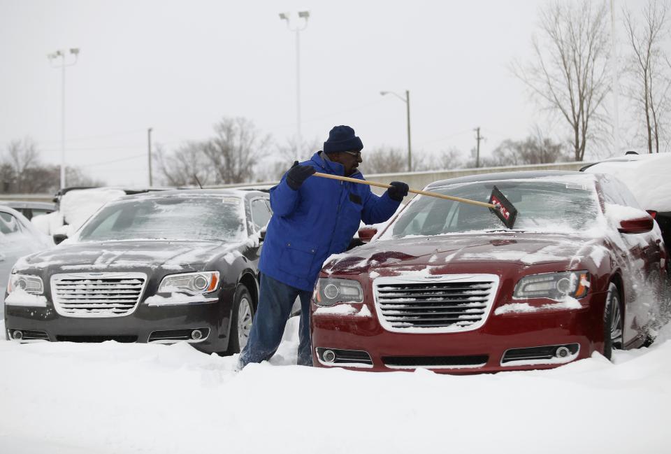 Car salesman Emerson clears snow off a Chrysler 300 at Bill Snethkamp dealership in Detroit