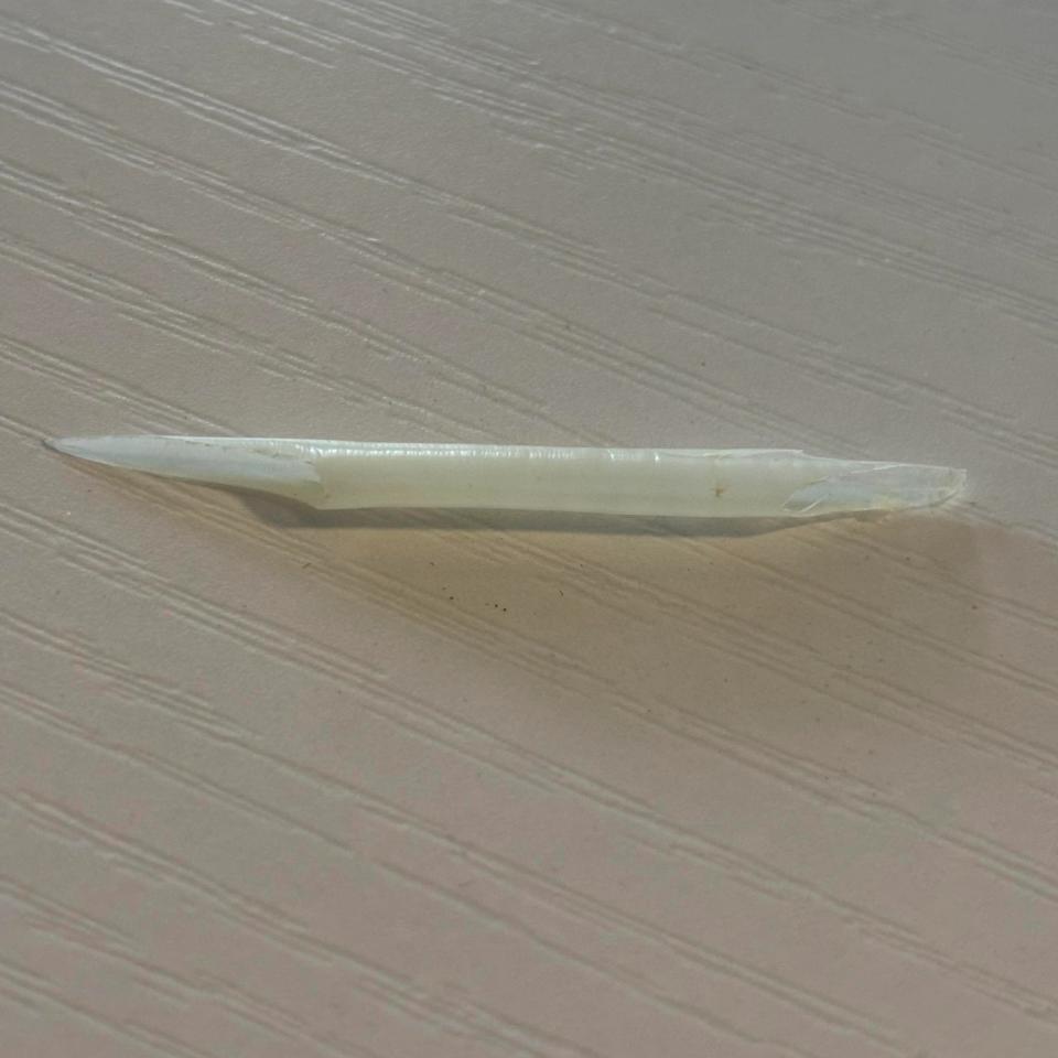 A white, slender object resembling a rolled joint lying on a textured surface