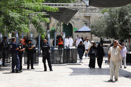 Tourists walk near Israeli police officers and recently installed metal detectors at an entrance to the compound known to Muslims as Noble Sanctuary and to Jews as Temple Mount in Jerusalem's Old City July 23, 2017. REUTERS/Ammar Awad