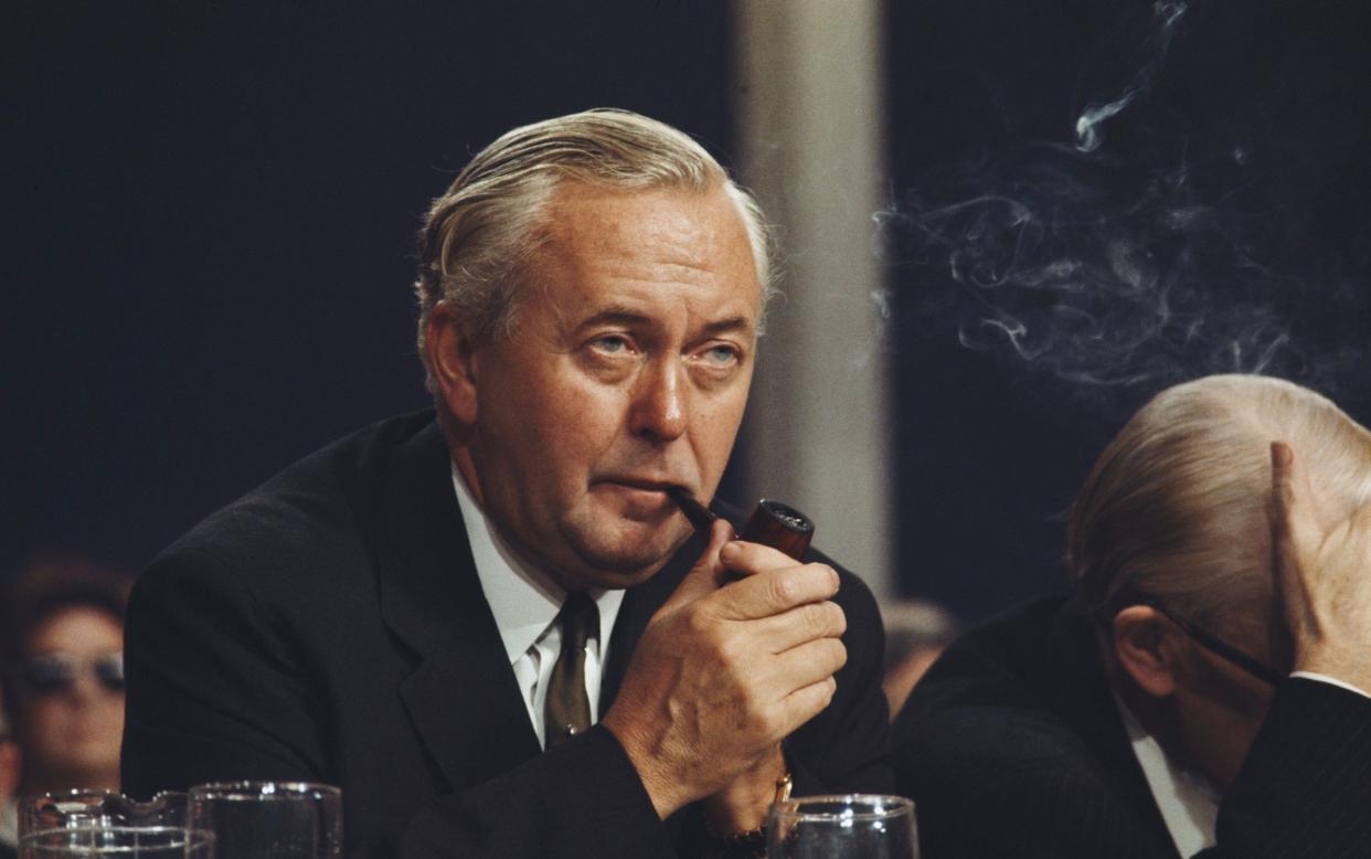 Harold Wilson smokes a pipe as he listens to a speech on the platform at the Labour Party annual conference