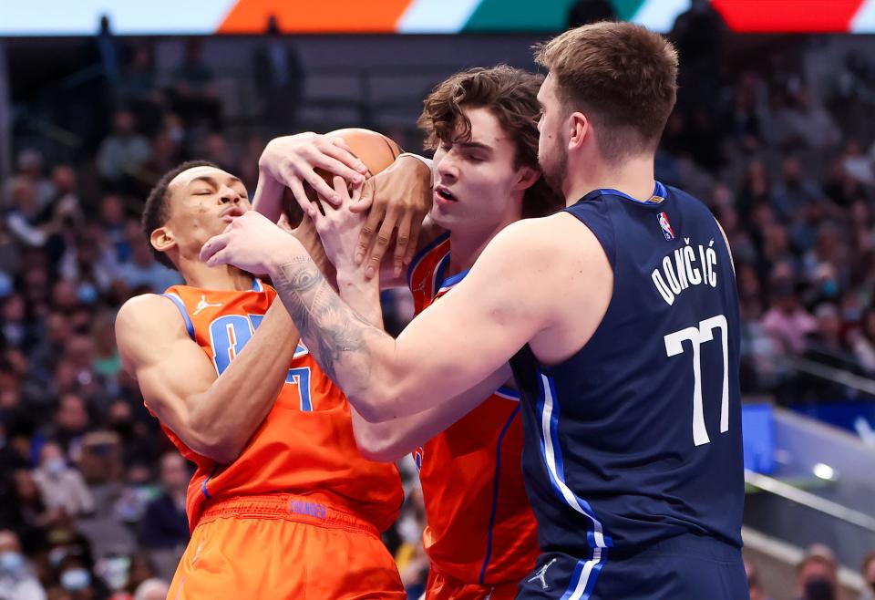 Dallas Mavericks guard Luka Doncic (77) battles for the ball with Oklahoma City Thunder forward Darius Bazley (7) and guard Josh Giddey during Monday night's NBA game at American Airlines Center.