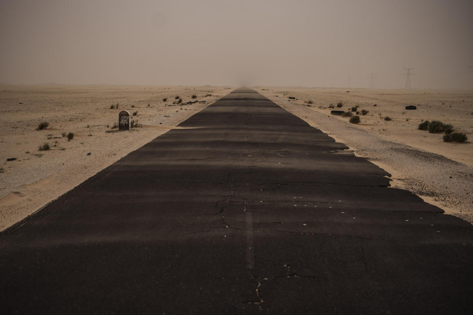 A strip of tarmac leading to the capital is partly covered by sand near Nouadhibou, Mauritania, Thursday, Dec. 2, 2021. (AP Photo/Felipe Dana)