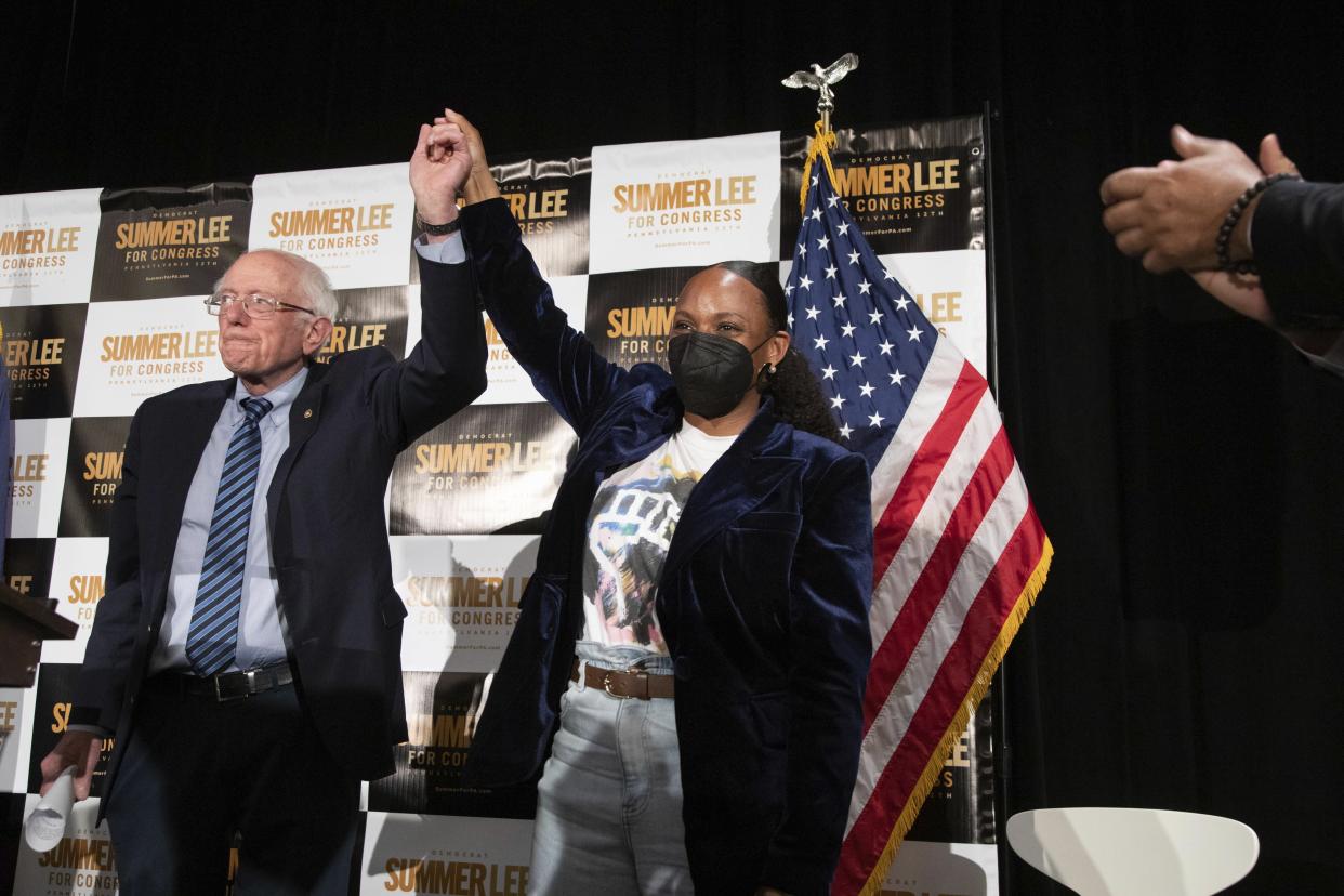 Senator Bernie Sanders and Summer Lee stand together with linked arms raised.