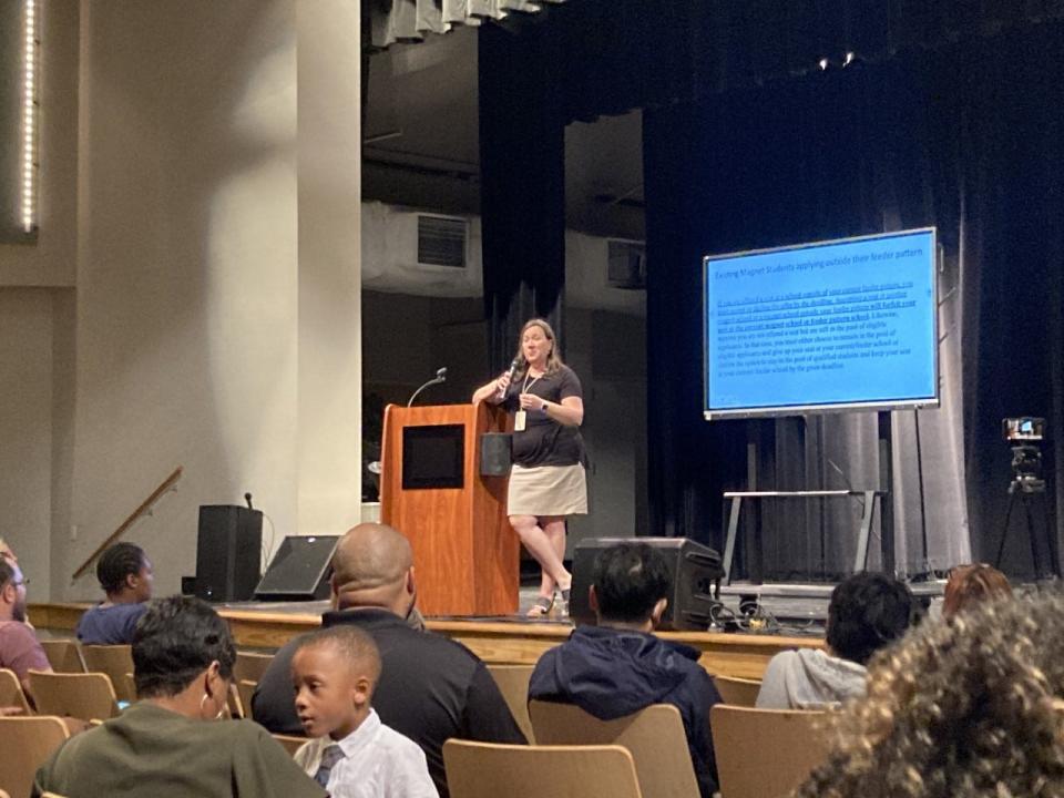 Families listen as Kristy Hatch, the district's director of strategy and innovation, goes through the steps to apply to a magnet school.