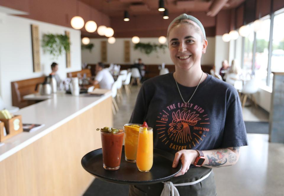 Cassie Alvarado holds a tray of cocktails at the Early Bird Eatery on Wayne Street in downtown South Bend. The owners of the restaurant chose its location because it was inside the riverfront district, which allows for affordable three-way liquor licenses.