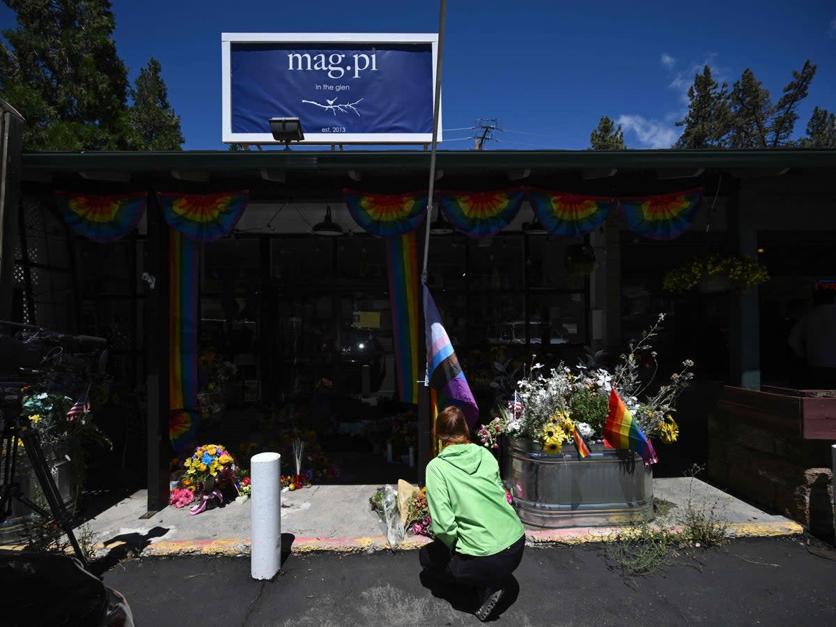 A resident leaves flowers at a makeshift memorial outside the Mag.Pi clothing store (AFP via Getty Images)