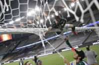 Matias Vina of Brazil's Palmeiras, top, takes a piece of the goal net after winning the Copa Libertadores final soccer match against Brazil's Santos at the Maracana stadium in Rio de Janeiro, Brazil, Saturday, Jan. 30, 2021. Palmeiras won 1-0. (Ricardo Moraes/Pool via AP)