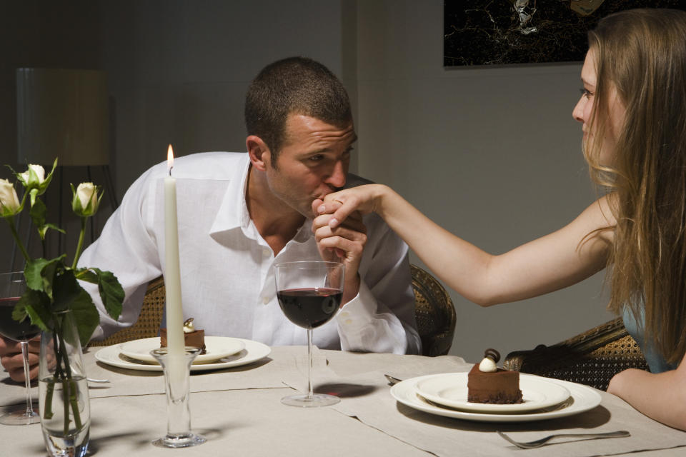 guy kissing his date's hand at dinner