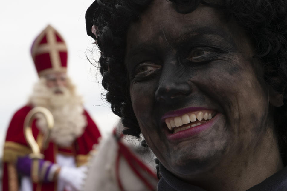 In this Saturday Nov. 16, 2019, file image, Zwarte Piet, or Black Pete, right, the controversial blackfaced sidekick of Saint Nicholas, rear left, walks in a parade in Scheveningen harbor, near The Hague, Netherlands. Activists spurred by the Black Lives Matter protests in the United States are seeking to shed more light on the Dutch colonial past and tackle what they call ingrained racism and discrimination in this nation that was once known as a beacon of tolerance. (AP Photo/Peter Dejong, File)