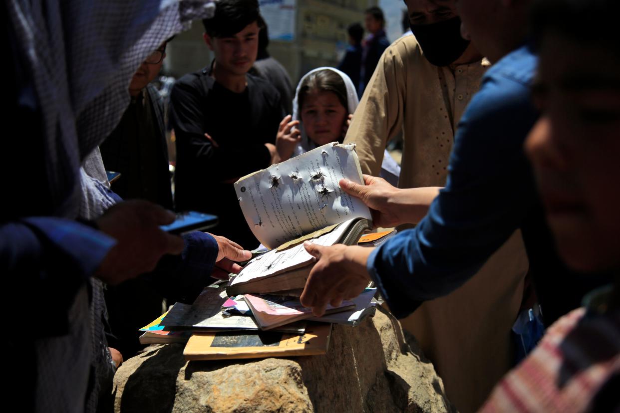 <p>Afghans go through belongings left behind after deadly bombings on Saturday near a school in Kabul, Afghanistan, Sunday, on 9 May, 2021</p> (AP)