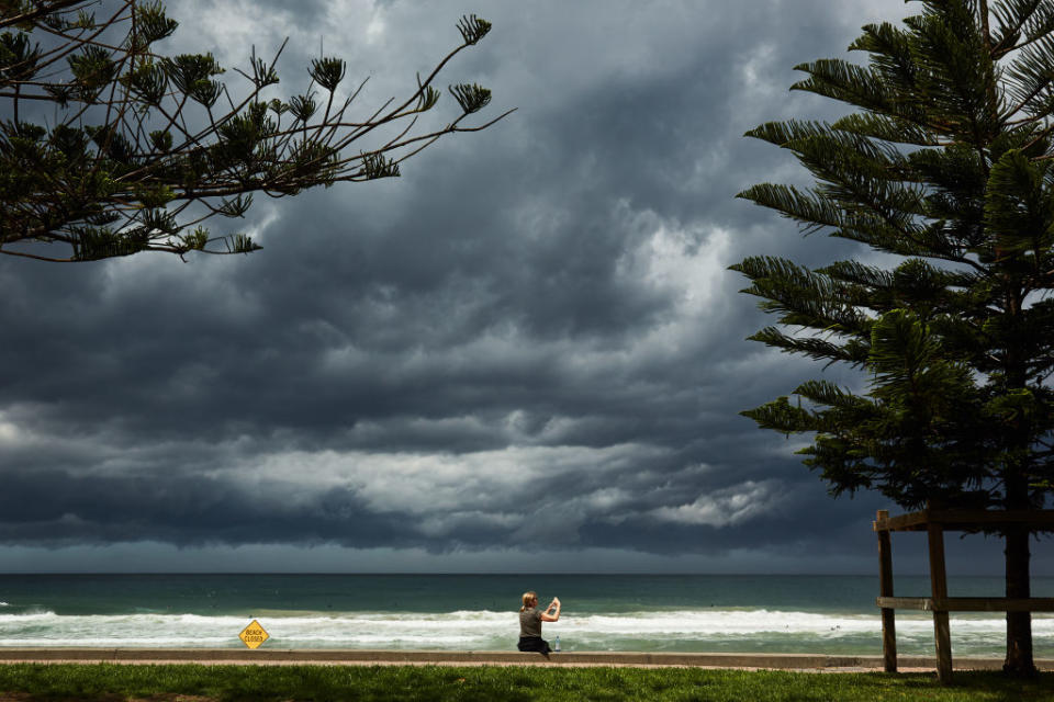 A lady takes a photo of an approaching storm at Manly Beach in Sydney, Australia. 