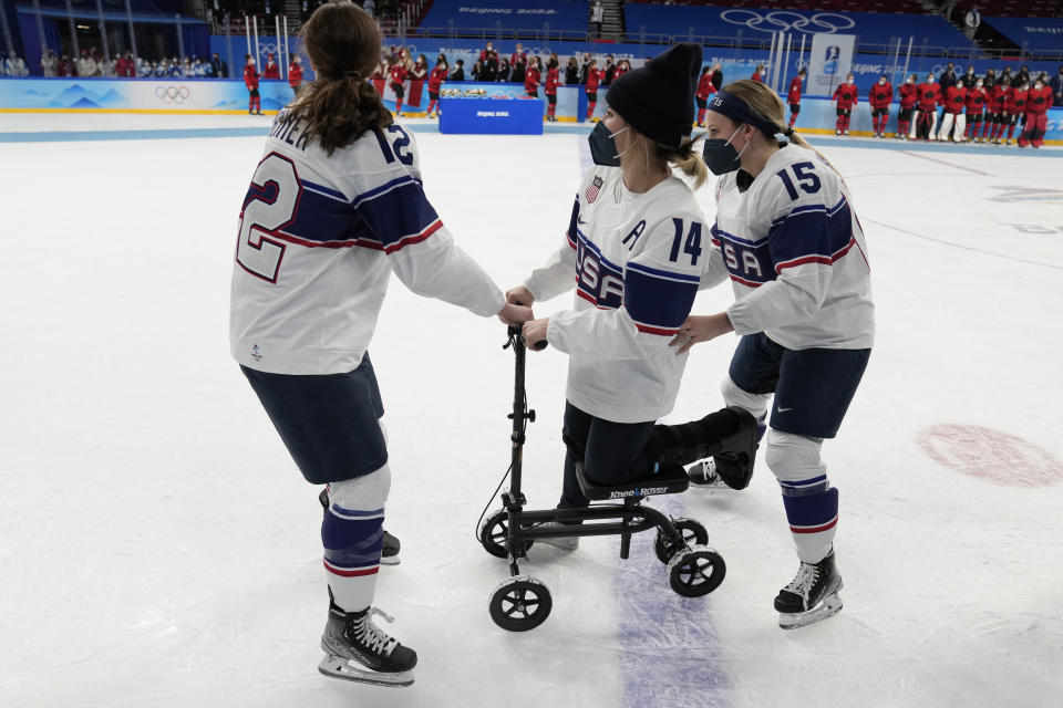 United States' Kelly Pannek, left, and United States' Savannah Harmon help United States' Brianna Decker, center, on the ice after losing to Canada in the women's gold medal hockey game at the 2022 Winter Olympics, Thursday, Feb. 17, 2022, in Beijing. (AP Photo/Petr David Josek)