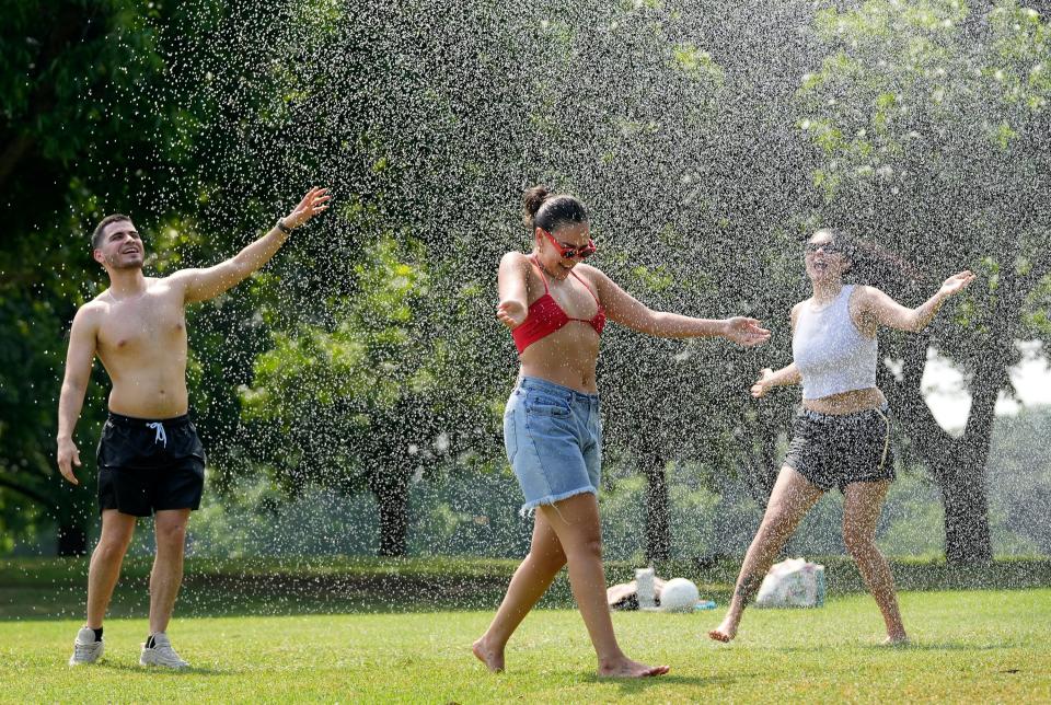 Samuel Gomez, Jacki Rivera and her sister Amy Rivera, right, cool off in the irrigation sprinkler on the Great Lawn at Zilker Park when it was 93 degrees Monday May 20, 2024.