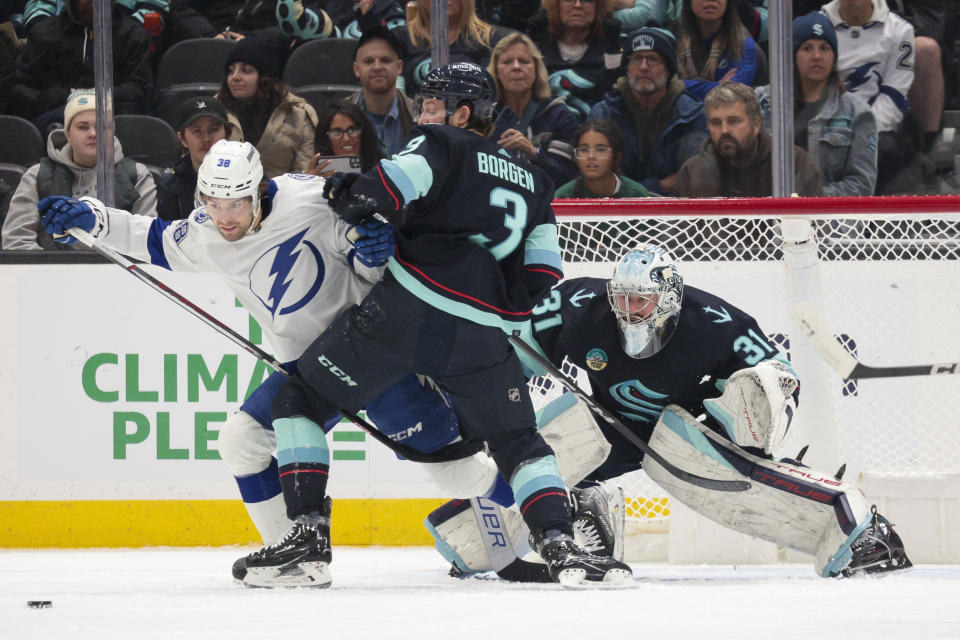 Seattle Kraken goaltender Philipp Grubauer (31) tracks the puck as defenseman Will Borgen (3) defends against Tampa Bay Lightning left wing Brandon Hagel (38) during the first period of an NHL hockey game Saturday, Dec. 9, 2023, in Seattle. (AP Photo/Jason Redmond)