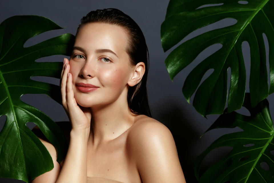 Beauty. Young woman portrait with fresh green exotic tropical leafs.