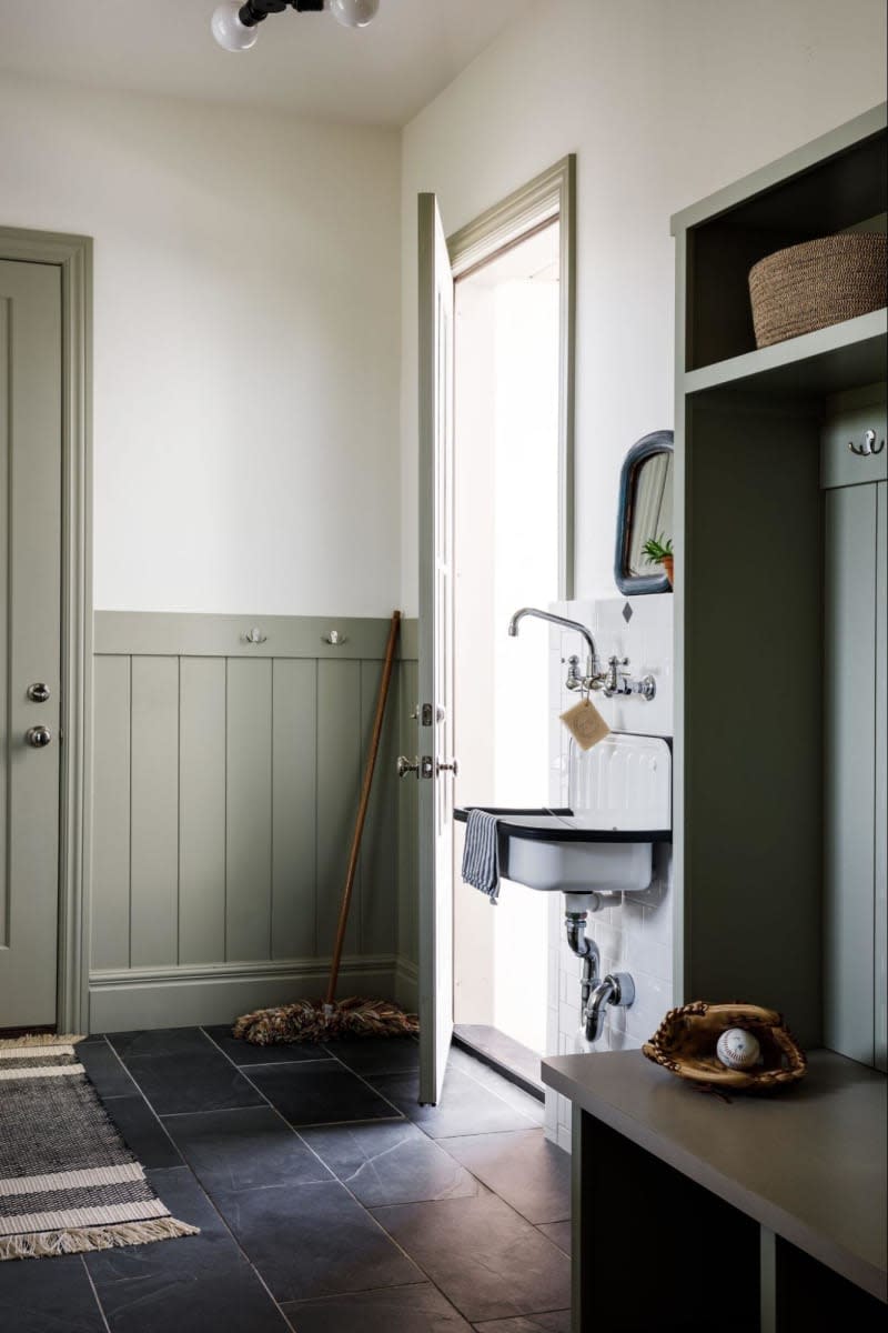 Green half wall tongue and groove, vintage sink, built out bench and cubbies, dark tile floor