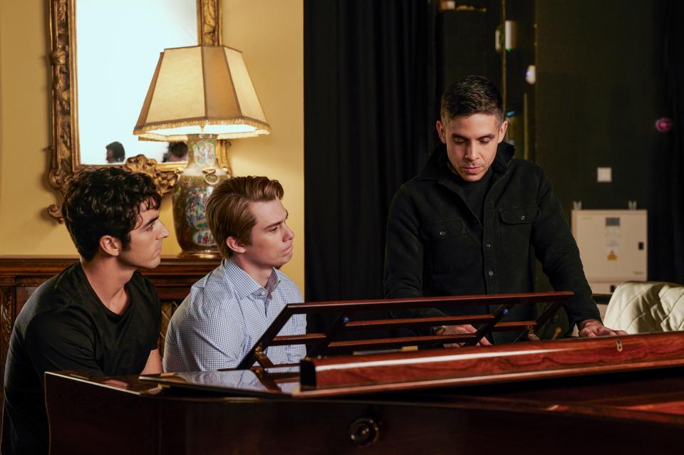 taylor zakhar perez, nicholas galitzine sit close at a piano, while matthew lópez gestures to a note in front of him nearby