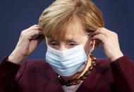 German Chancellor Angela Merkel puts on her face mask after holding a joint news conference with Finance Minister Olaf Scholz after a virtual G20 summit meeting, at the Chancellery in Berlin, Germany, Sunday Nov. 22, 2020. (Hannibal Hanschke/Pool via AP)
