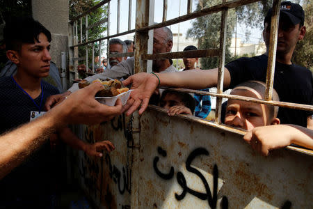 Residents receive food at a distribution point after the end of the battles between the Iraqi forces and Islamic State militants at Tayaran district in western Mosul, Iraq, April 30, 2017. REUTERS/Muhammad Hamed