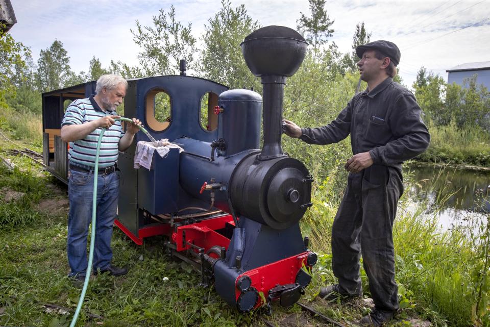 Pavel Chilin, left, and Sergei Terekhov prepare his steam locomotive to run along the miniature personal railway in Ulyanovka village outside St. Petersburg, Russia Sunday, July 19, 2020. It took Chilin more than 10 years to build the 350-meter-long miniature personal narrow-gauge railway complete with various branches, dead ends, circuit loops, and even three bridges.(AP Photo/Dmitri Lovetsky)