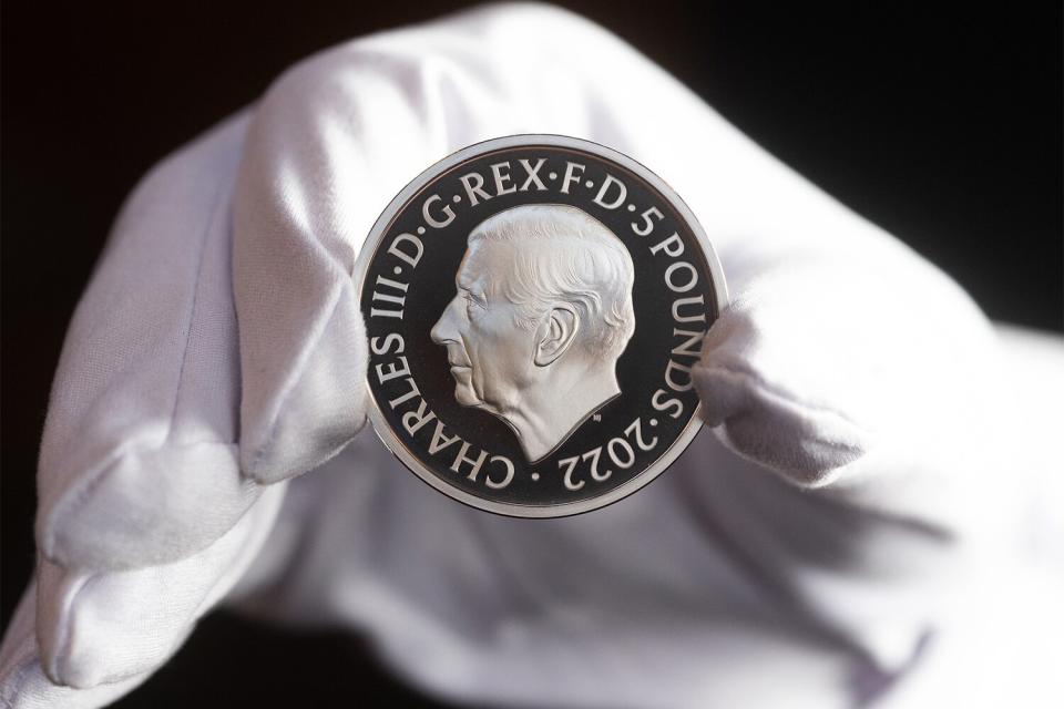 A five pound commemorative crown piece coin featuring the head of King Charles III held by an employee of the Royal Mint in London, UK, on Thursday, Sept. 29, 2022. The King's portrait which, sculptor Martin Jennings designed to face the opposite direction to his mothers, was approved by the monarch himself and seen by chancellor Kwasi Kwarteng in a process that kicked off after the Queen passed away. Photographer: Chris Ratcliffe/Bloomberg via Getty Images