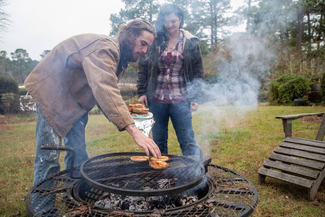 Sarah Baker and Scott Patterson toast bagels over an open flame Wednesday morning, Dec. 7, 2022 at Fox Lake Farm in Southern Pines. Two deliberate attacks on electrical substations in Moore County Saturday evening caused days-long power outages for tens of thousands of customers.