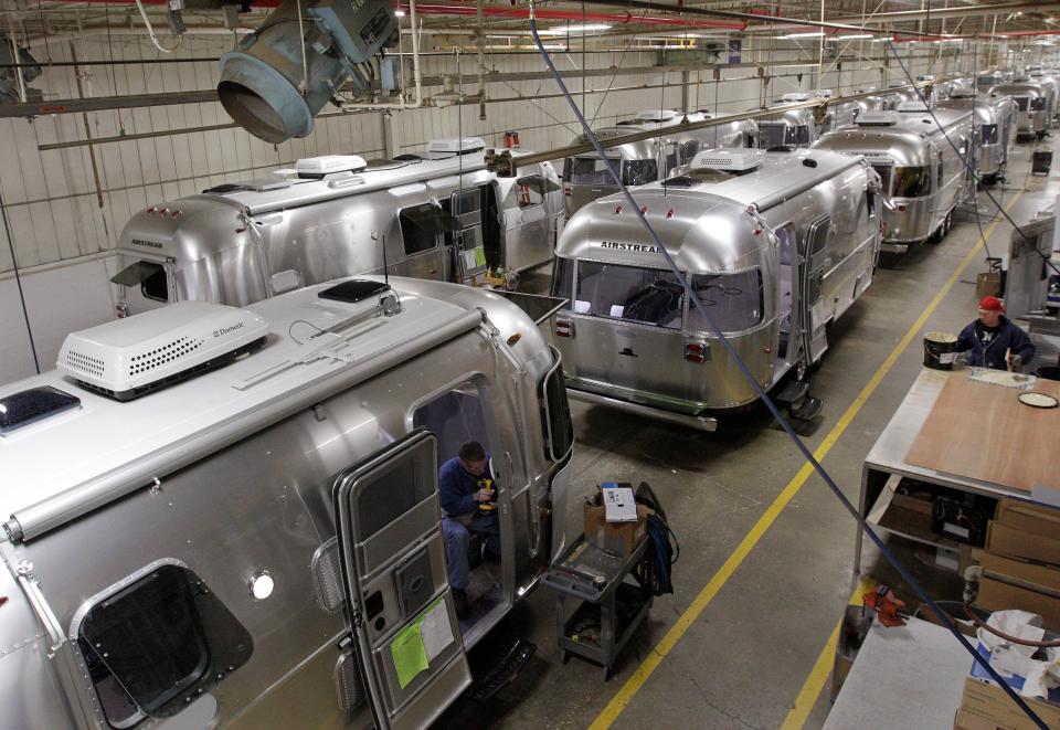 In this Oct. 22, 2014 photo, Airstream travel trailers line the factory floor as they are assembled at the Airstream factory in Jackson Center, Ohio. Not only are the Airstream trailers still being built by hand at the same western Ohio site that has produced them for the past 60 years, but the company also can't roll them out of there fast enough to meet the demand these days. (AP Photo/Jay LaPrete)