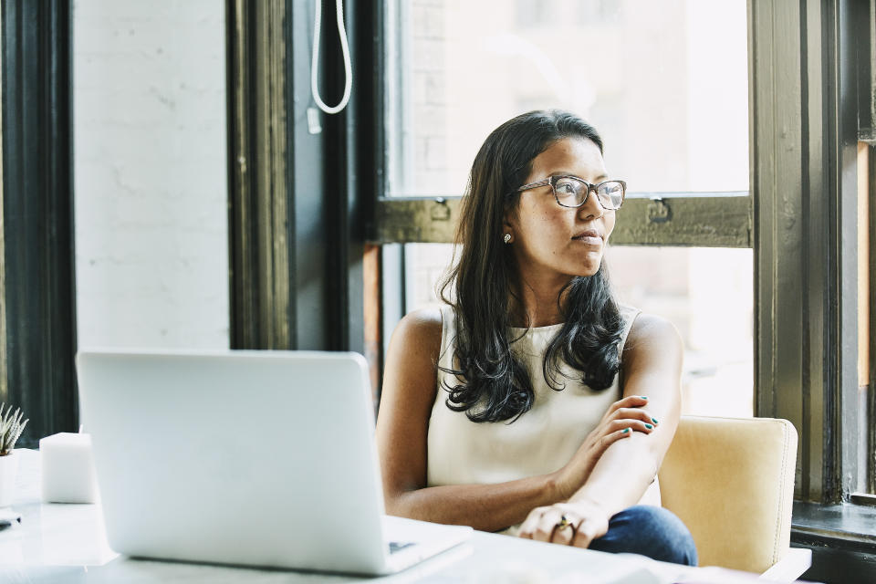 Businesswoman looking out window while seated at desk in office