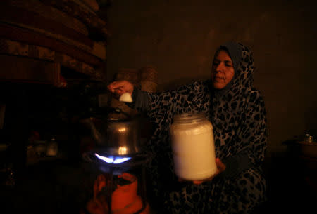 A Palestinian woman makes tea as she uses candle light during power cut in the kitchen of her house in Khan Younis in the southern Gaza Strip July 3, 2017. REUTERS/Mohammed Salem