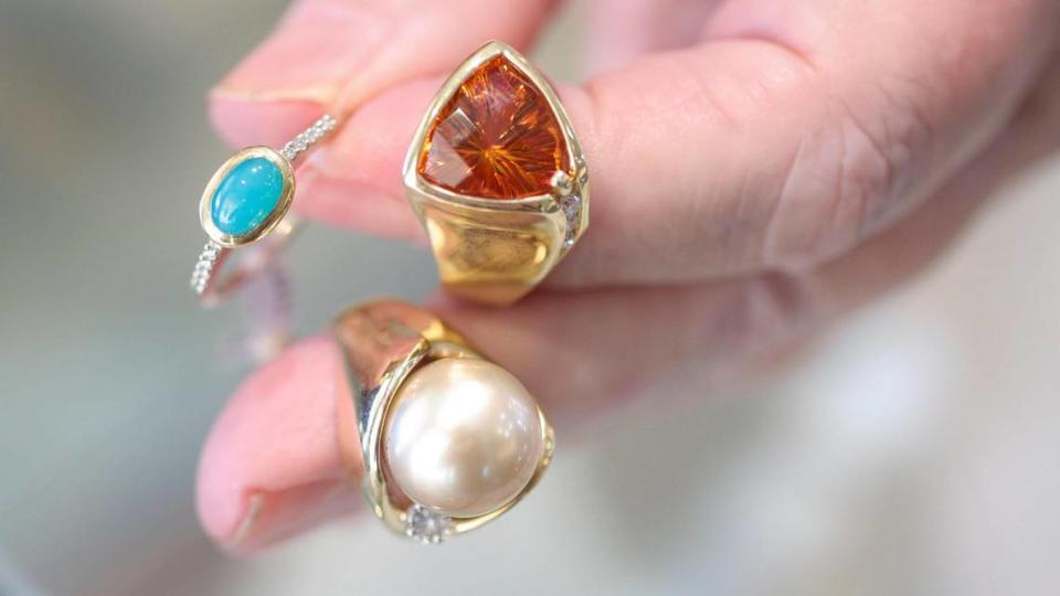 Claudia Alexander-Denny holds three rings she designed at Alexander-Denny Jewelry Studio in Cambria, from left, chrysocolla with 18-carat gold and diamonds, citrine with 18-carat gold and diamonds, and Tahitian pearl with 18-carat gold and diamonds. David Middlecamp/dmiddlecamp@thetribunenews.com
