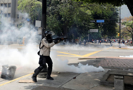 A riot police oficer fires tear gas as demonstrators rally against Venezuela's President Nicolas Maduro's government in Caracas, Venezuela April 10, 2017. REUTERS/Carlos Garcia Rawlins