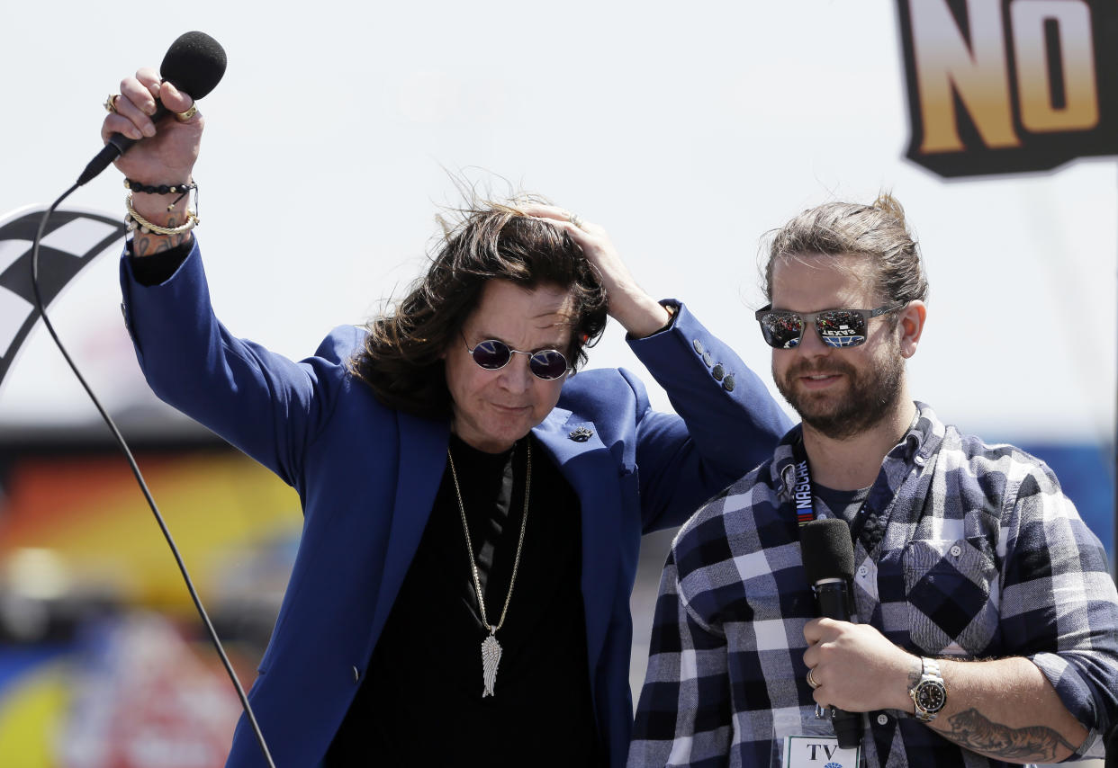 Entertainer Ozzy Osbourne, left, and his son Jack acknowledge cheers from fans during a ceremony before a NASCAR Cup Series auto race at Texas Motor Speedway in Fort Worth, Texas, Sunday, April 9, 2017. (AP Photo/Tony Gutierrez)