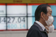 People walk by an electronic stock board of a securities firm in Tokyo, Monday, Jan. 27, 2020. Shares tumbled Monday in the few Asian markets open as China announced sharp increases in the number of people affected in an outbreak of a potentially deadly virus. (AP Photo/Koji Sasahara)