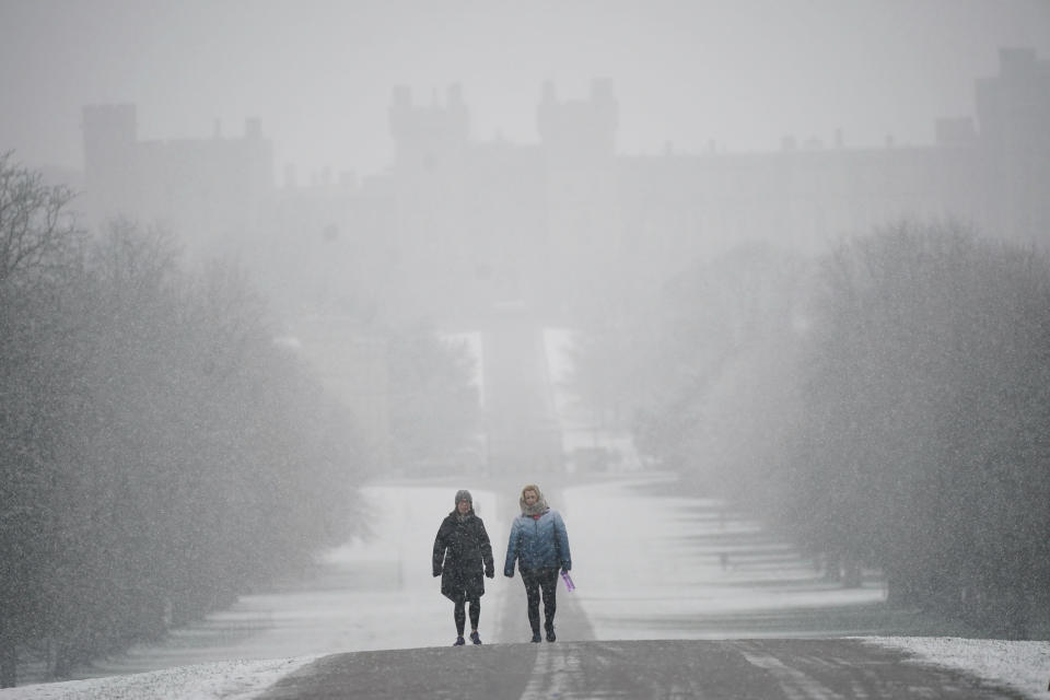 People walk under the snow along the Long Walk towards Windsor Castle, Berkshire, Wednesday March 8, 2023. Parts of the UK wake up to snow and a yellow weather warning. (Yui Mok/PA via AP)