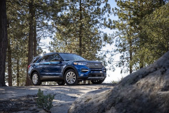 A blue 2020 Ford Explorer Limited, parked on a boulder in a forest