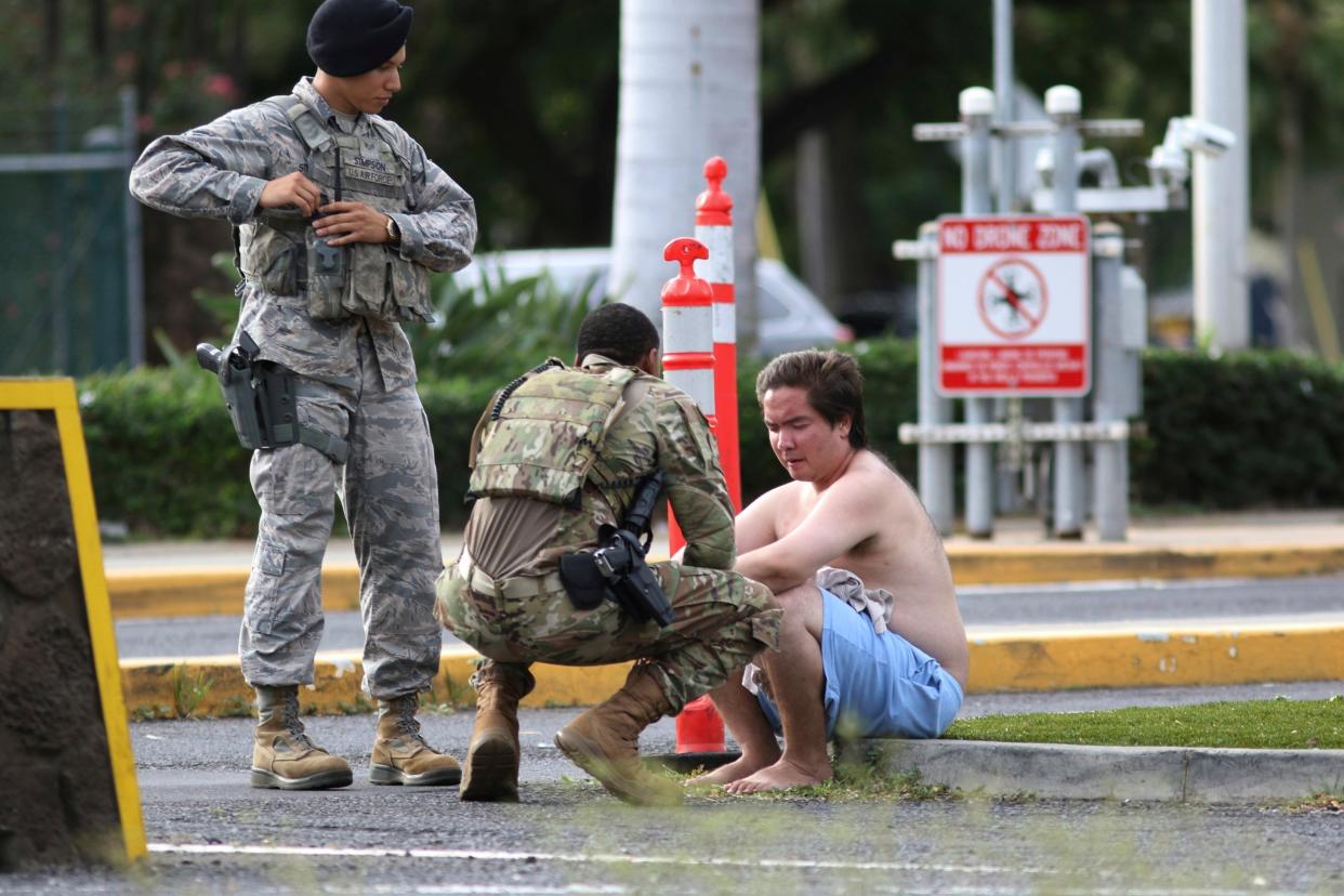 Security forces attend to an unidentified male outside the main gate at Joint Base Pearl Harbor-Hickam on Wednesday following a shooting: AP