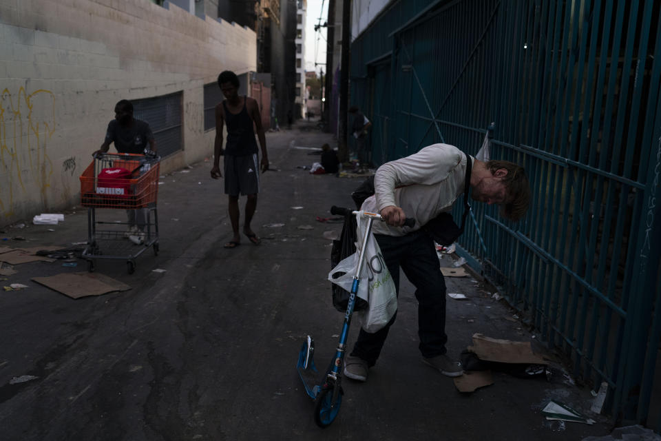 A drug addict holds the handle of a scooter as he falls asleep after smoking fentanyl in Los Angeles, Tuesday, Aug. 9, 2022. For too many people strung out on the drug, the sleep that follows a fentanyl hit is permanent. The highly addictive and potentially lethal drug has become a scourge across America and is taking a toll on the growing number of people living on the streets of Los Angeles. (AP Photo/Jae C. Hong)