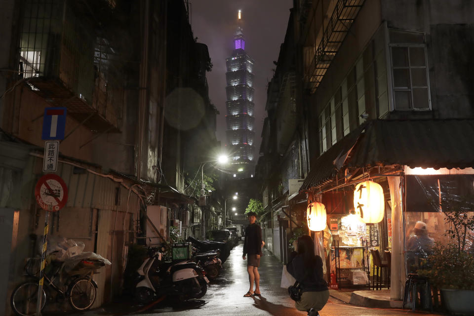 FILE - People take photos in an old-style neighborhood with the Taipei 101 building in the background in Taipei, Taiwan, on May 7, 2023. Taiwan’s government is racing to counter China’s military, but many on the island say they don’t share the sense of threat. (AP Photo/Chiang Ying-ying, File)