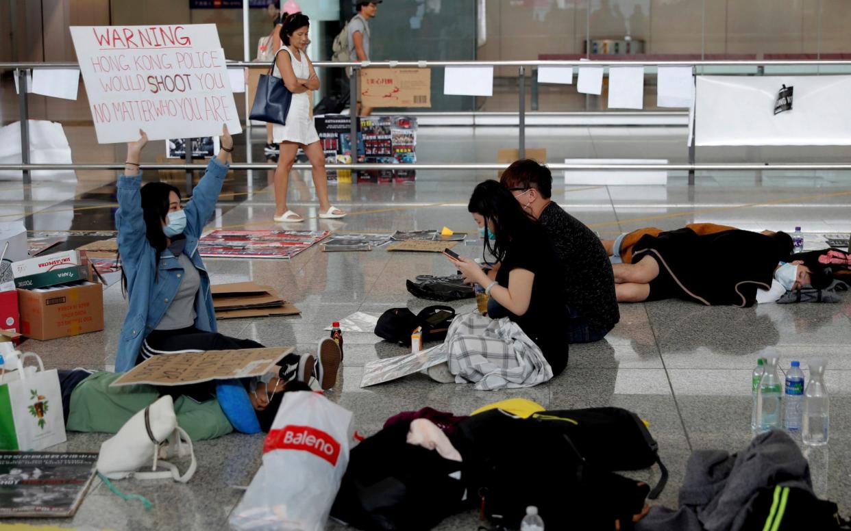 A protester shows a placard to travellers as they continue their sit-in rally at the airport in Hong Kong on Wednesday - AP