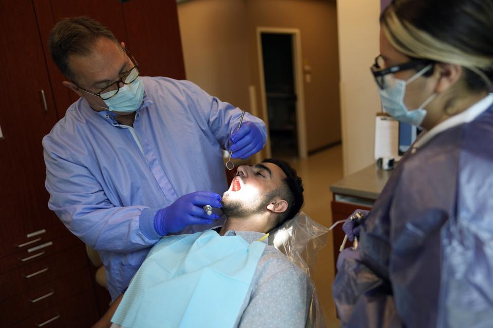 Dentist Michael Wisnoski, left, checks the teeth of Abdul Wasi Safi during a clinic visit, Wednesday, April 26, 2023, in Houston. Safi's days since his release from a Texas immigration detention center have been filled with medical appointments while living in Houston with his brother. (AP Photo/David J. Phillip)