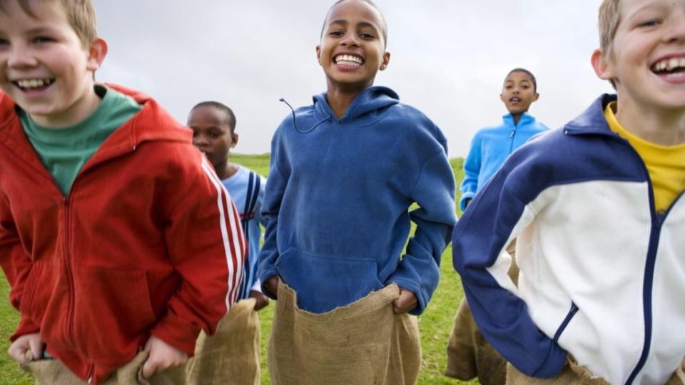 Group of boys aged 10-13 having a sack race outdoors