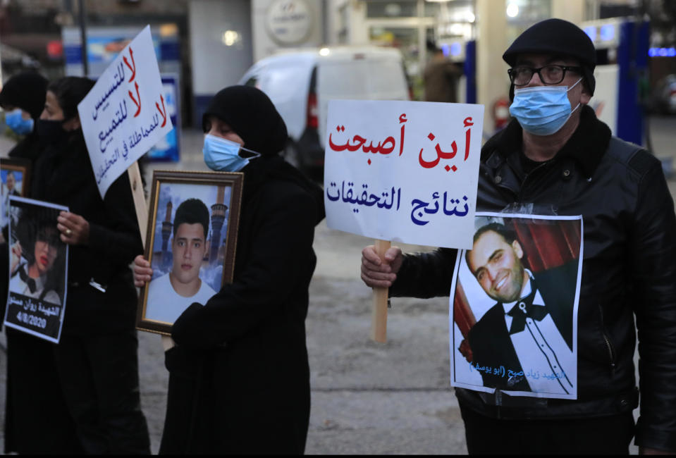 Relatives of victims of the Aug. 4, 2020 Beirut port explosion hold portraits of their loved one who killed during the explosion, during a sit-in outside the Justice Palace, in Beirut, Lebanon, Thursday, Feb. 18, 2021. Lebanon's highest court asked the chief prosecutor investigating last year's massive Beirut port explosion to step down, following legal challenges by senior officials he had accused of negligence that led to the blast, a judicial official and the country's official news agency said. The Arabic placard reads:"where are the result of the investigation." (AP Photo/Hussein Malla)