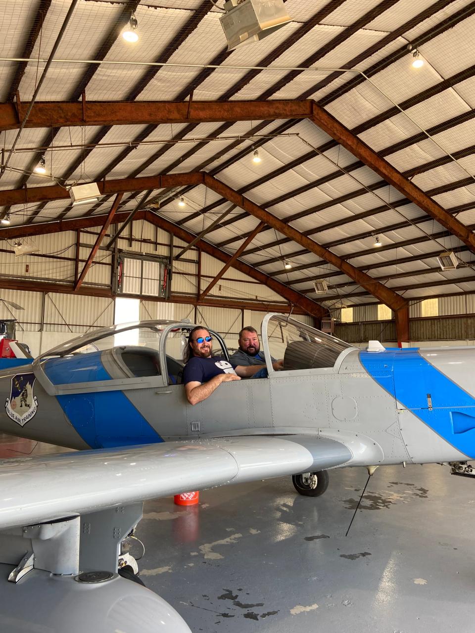 Brandon Goldsmith, president River Valley Film Society and John Wright, director of Blue Air Training, sit together in a plane inside the airplane hangar.